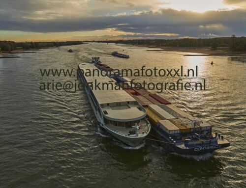 kvb Contargo afvarend op de rivier de Waal met het casco van een nieuw passagiersschip van Scylla opzij